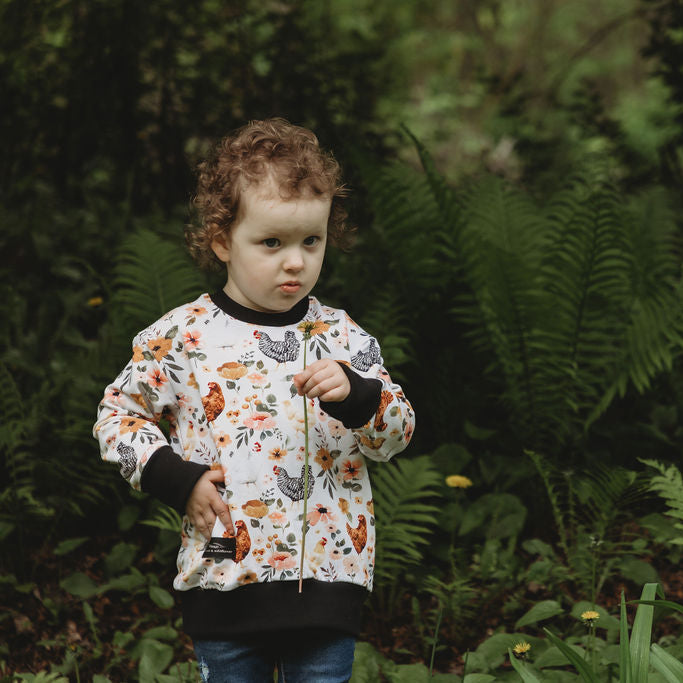 Child standing in a forest with ferns and greenery