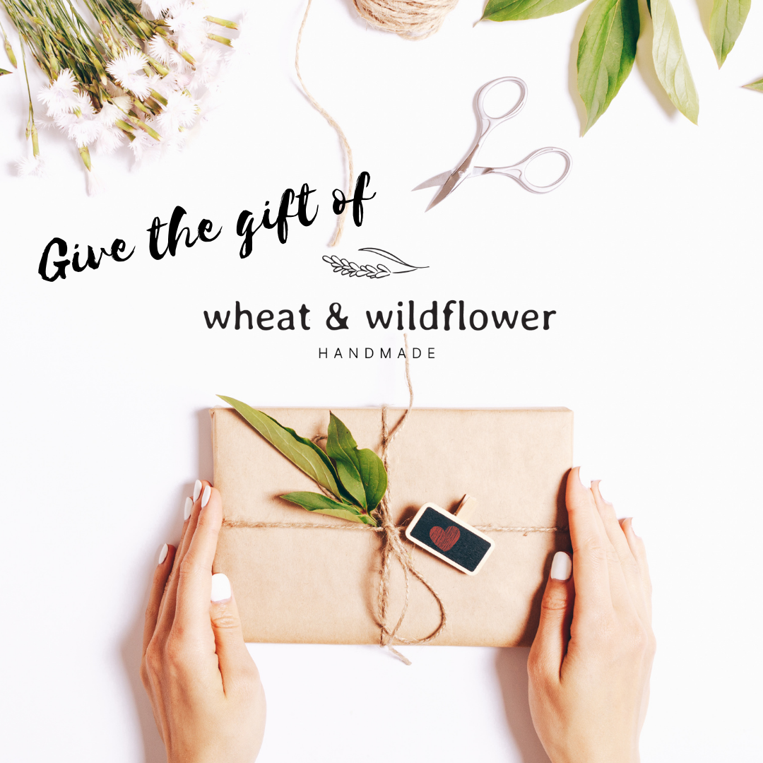 Give the Gift of Wheat and Wildflower Handmade with a giftcard.  Image shows a box wrapped in brown paper and tied with twine with a sprig of leaves on top and flowers beside.